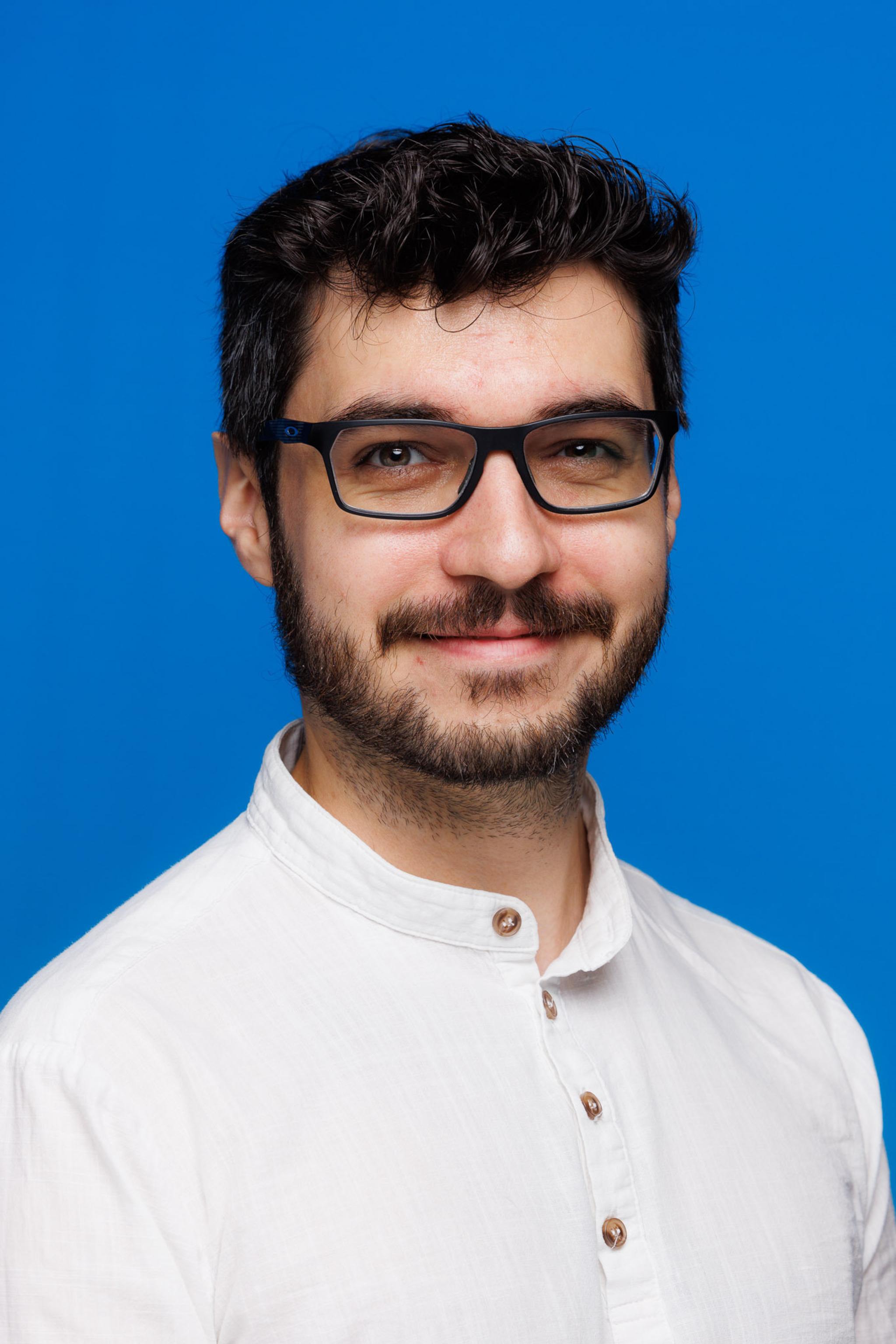 An image with a blue background of Charlie wearing a white shirt.